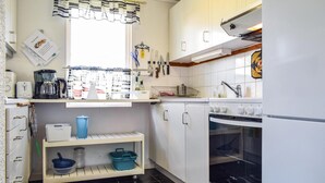 Una cocina compacta con armarios blancos, horno integrado y cafetera.