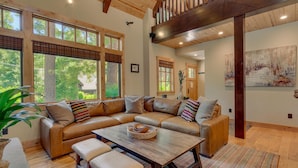 A spacious living room with a large L-shaped sectional sofa, a wooden coffee table, and a bench. - Holly Hideaway - TLUXP (Tahoe City)