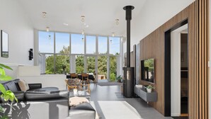 Ett modernt vardagsrum med en öppen spis, stora fönster och en matplats.