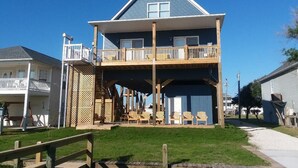 Une maison à deux étages dotée d’un balcon, d’une terrasse en bois et d’un espace salon extérieur.