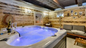 A wooden cabin interior with a hot tub, a sofa, and a small table with candles. - Gorgeous home in Kupljenovo (Kupljenovo)