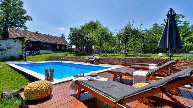 A backyard with a swimming pool, lounge chairs, and a wooden deck. - Gorgeous home in Kupljenovo (Kupljenovo)