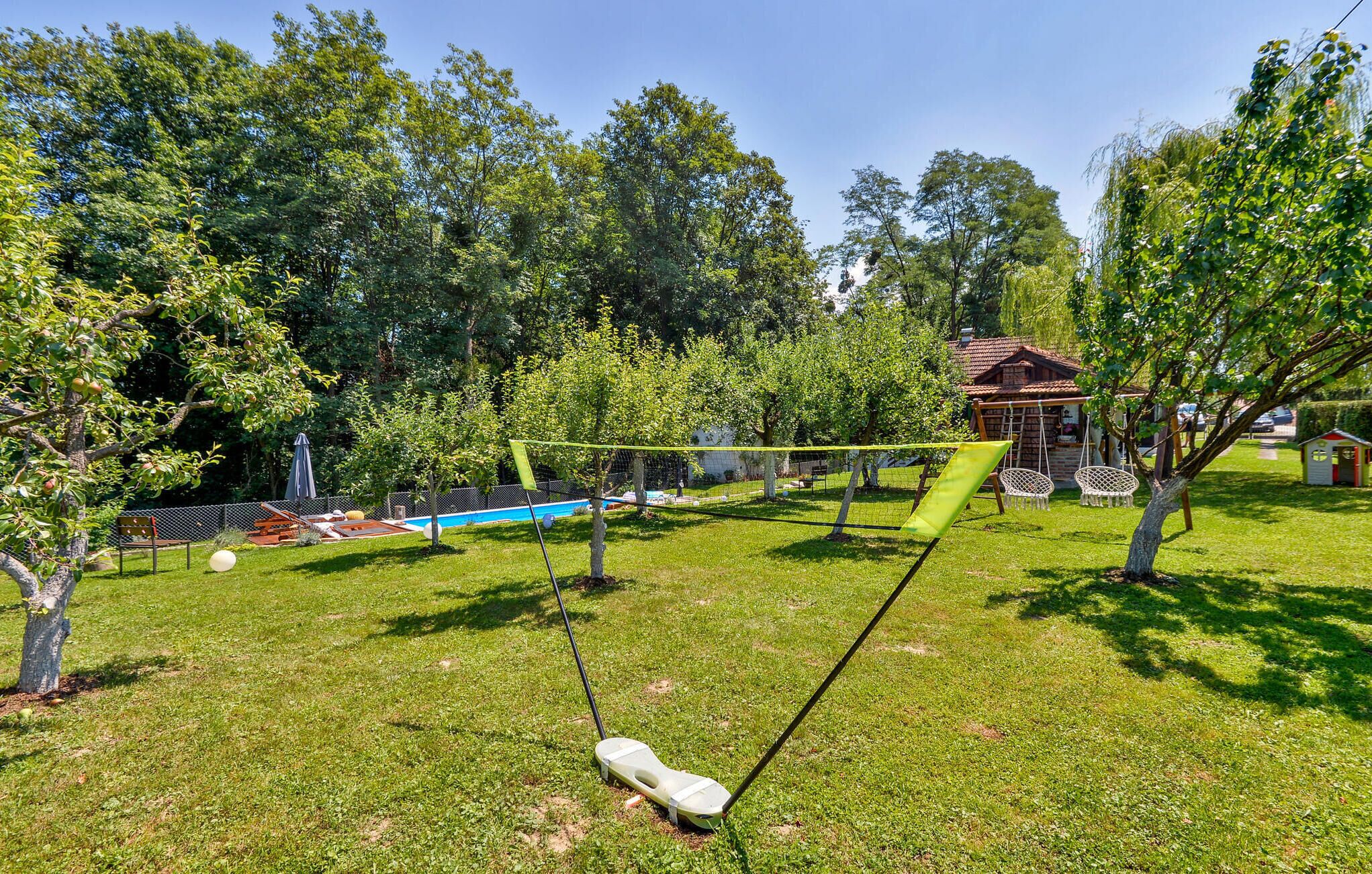 A grassy backyard with a swing set, a small pool, and a wooden structure.
