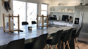 A modern kitchen with a central island, black chairs, and a stainless steel refrigerator.