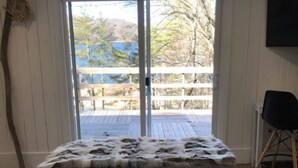 A bedroom with a bed, a view of a wooden deck, and a chair.