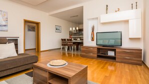 A modern living room with a sofa, coffee table, TV, and dining area. - Amazing home in Kozino (Kozino)