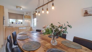 A dining area with a wooden table, woven placemats, and a vase with flowers. - Awesome home in Wemeldinge with sauna (Wemeldinge)