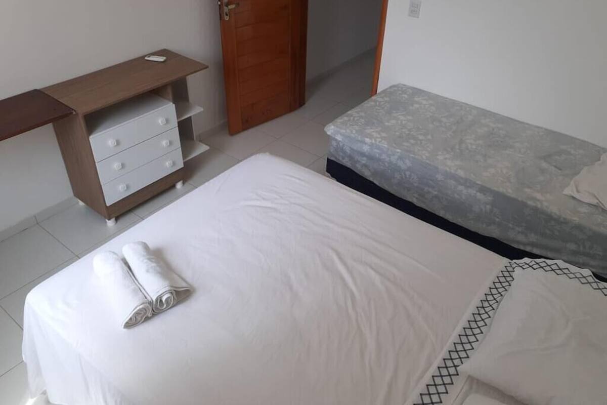 Un dormitorio con cama, un escritorio de madera con cajones y una puerta.