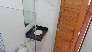 A small bathroom with a toilet, sink, and mirror. - Barcelona Beach Residence (Aracati)