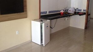 A compact kitchen with a built-in TV, a small refrigerator, and a tiled backsplash. - Barcelona Beach Residence (Aracati)