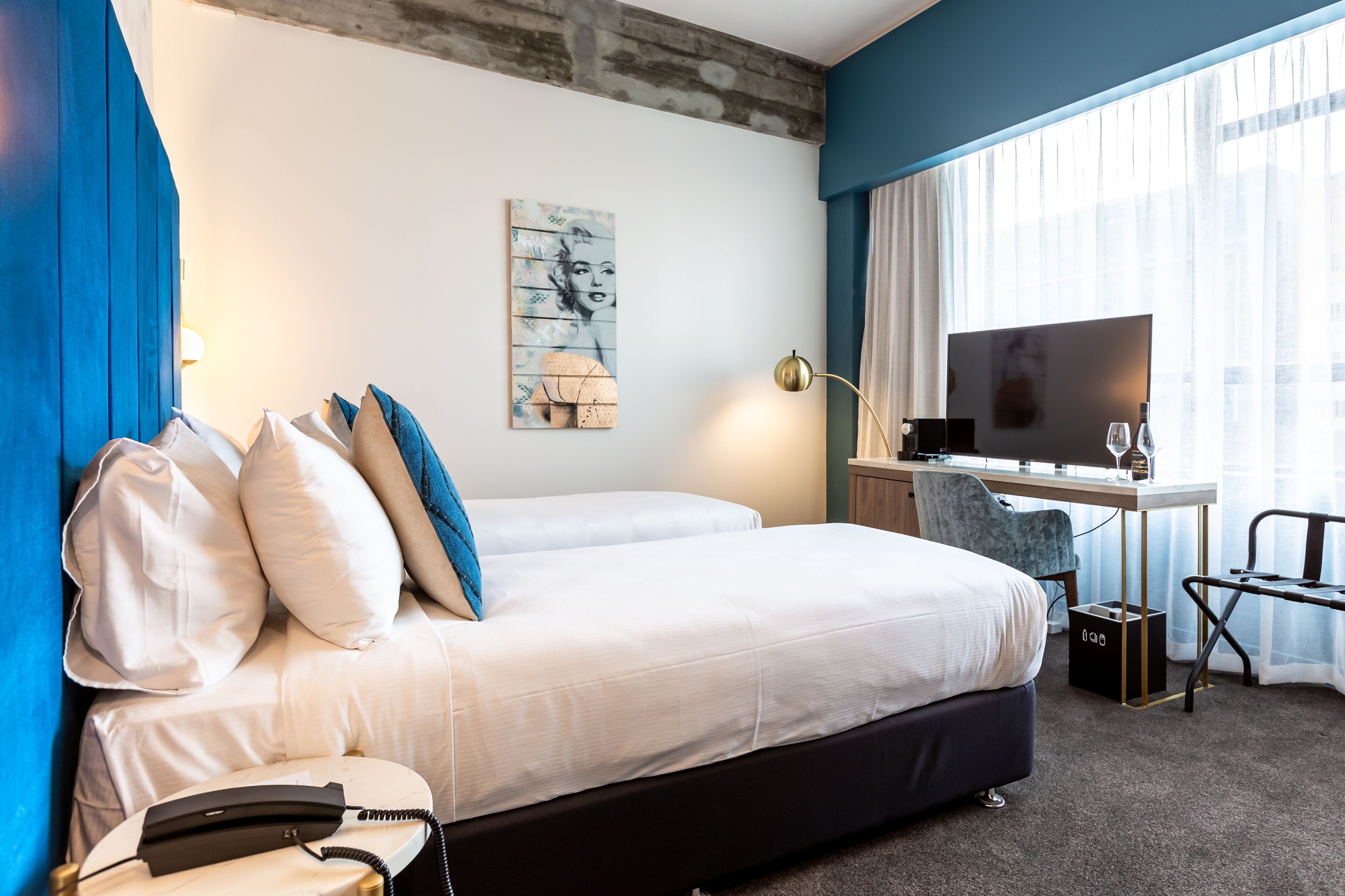 A hotel room with a large bed, a desk with a computer, a TV, and a telephone.