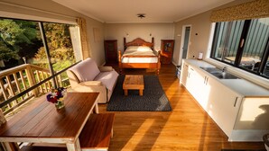 Un dormitorio con una cama grande, un sofá, una mesa de madera y una zona de cocina con fregadero.