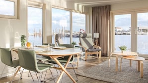 A modern dining area with a view of a marina, featuring a round table, green chairs, and a small side table with a lamp. - Amazing ship in Aalsmeer with harbor view (Aalsmeer)