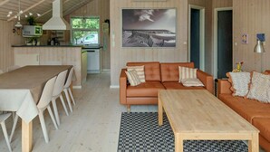 A cozy cabin interior with a dining area, a sofa, and a wooden table.