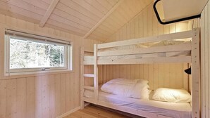 A bunk bed room with wooden walls and a window.