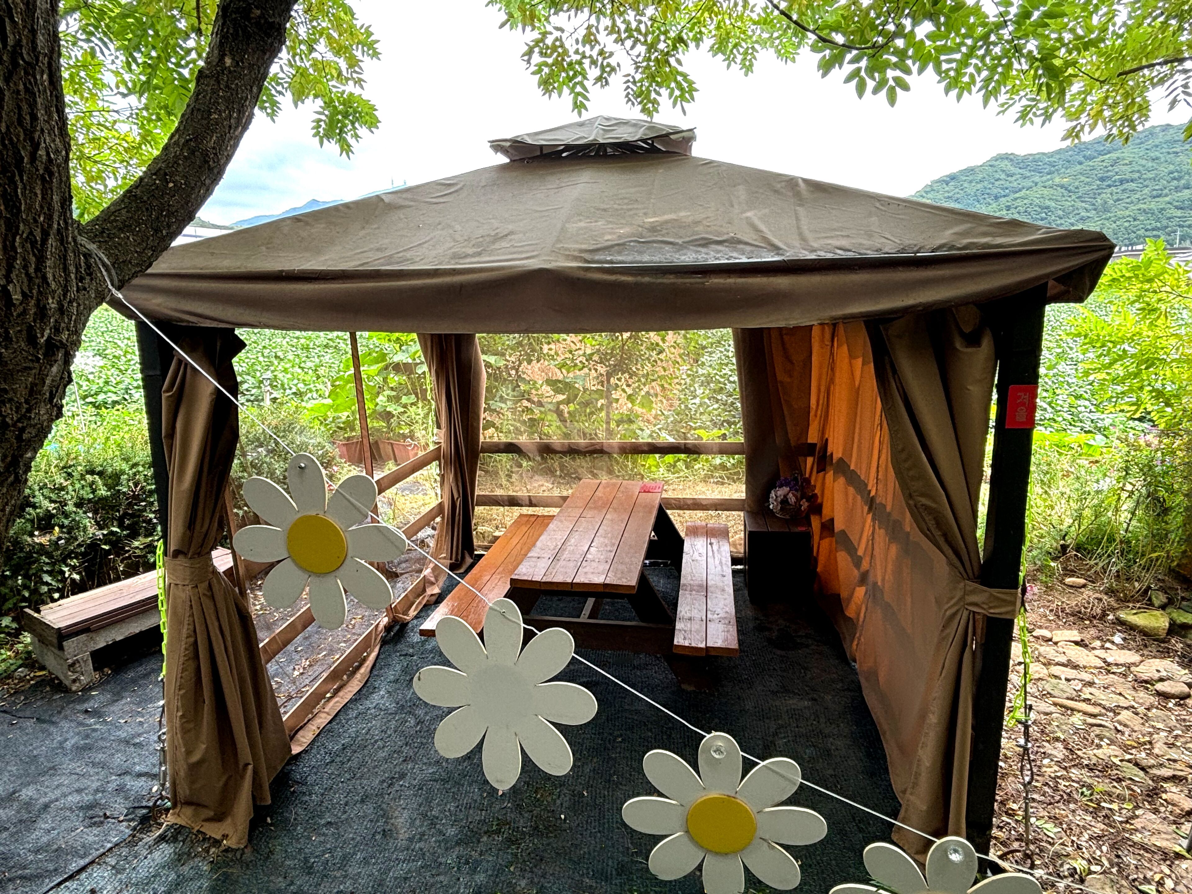 Uma tenda rústica com uma mesa de piquenique e uma guirlanda de flores.