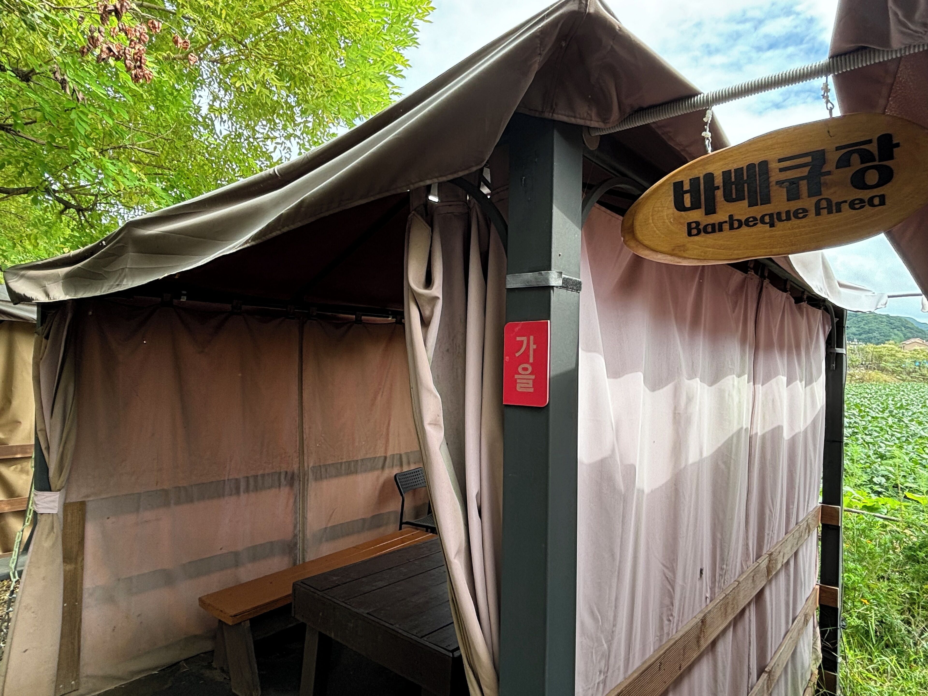 Une tente avec une pancarte indiquant un espace barbecue.