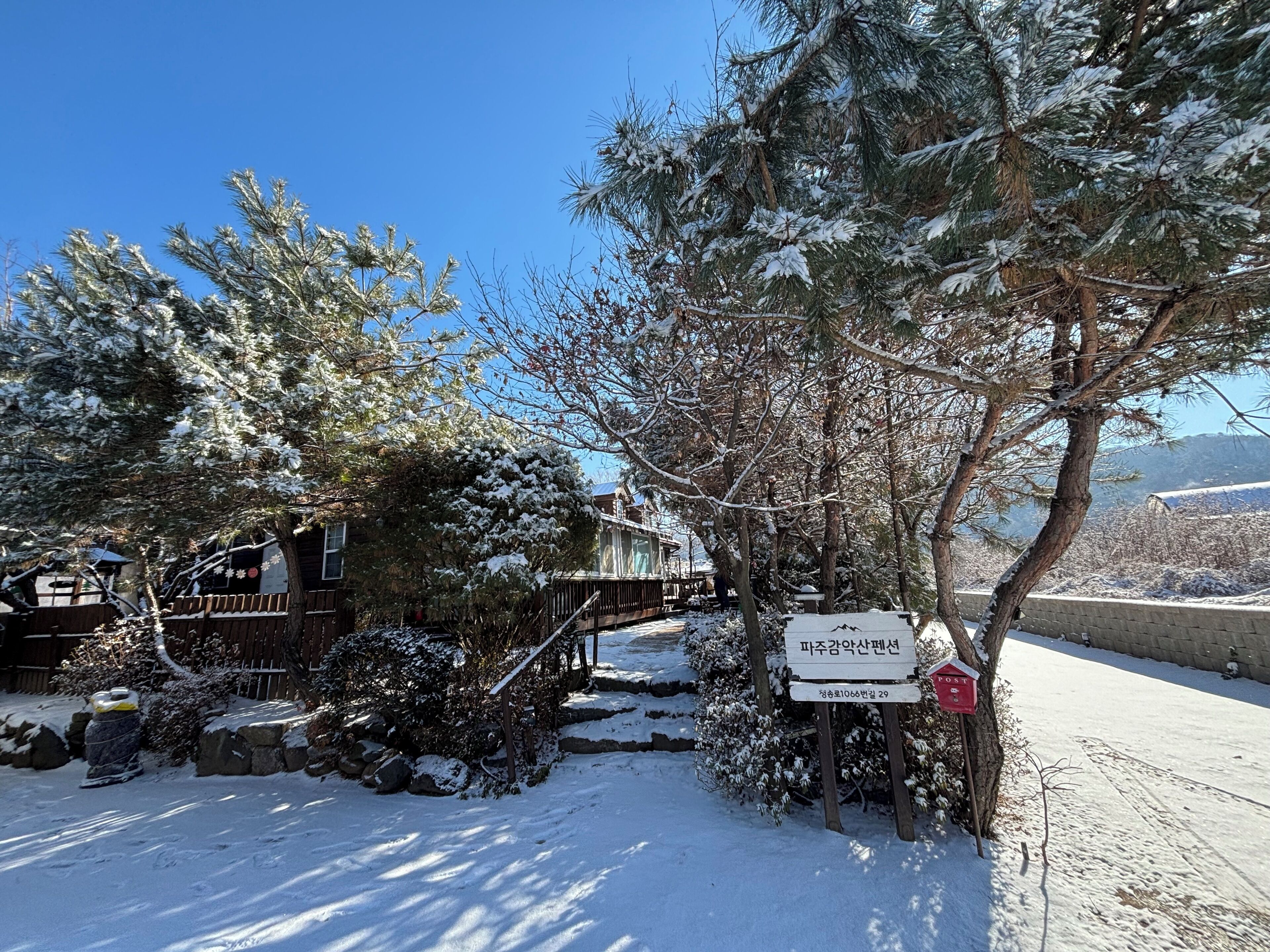 A snow-covered outdoor area with a wooden deck and a sign indicating a location.