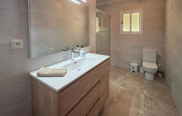 Ein modernes Badezimmer mit einem großen Waschbecken, Spiegel und Toilette.