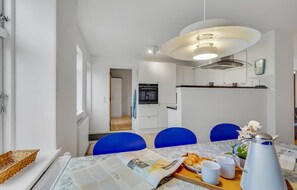 A modern kitchen with white cabinets, a built-in oven, and a stainless steel range hood.