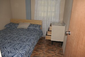 A bedroom with a bed, a wooden headboard, a patterned bedspread, a small white cabinet, and a wooden door. - Comfort, Beautiful Scenery, Warmth and Relaxation all mixed into one apartment (Pont Cassé)