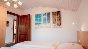 Un dormitorio con cama, una puerta de madera y una lámpara en el techo.