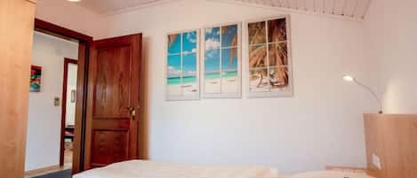 Een slaapkamer met een bed, een houten deur en een plafondlamp.