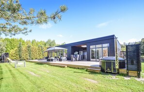 Una casa moderna con patio, mobiliario exterior y zona de barbacoa.