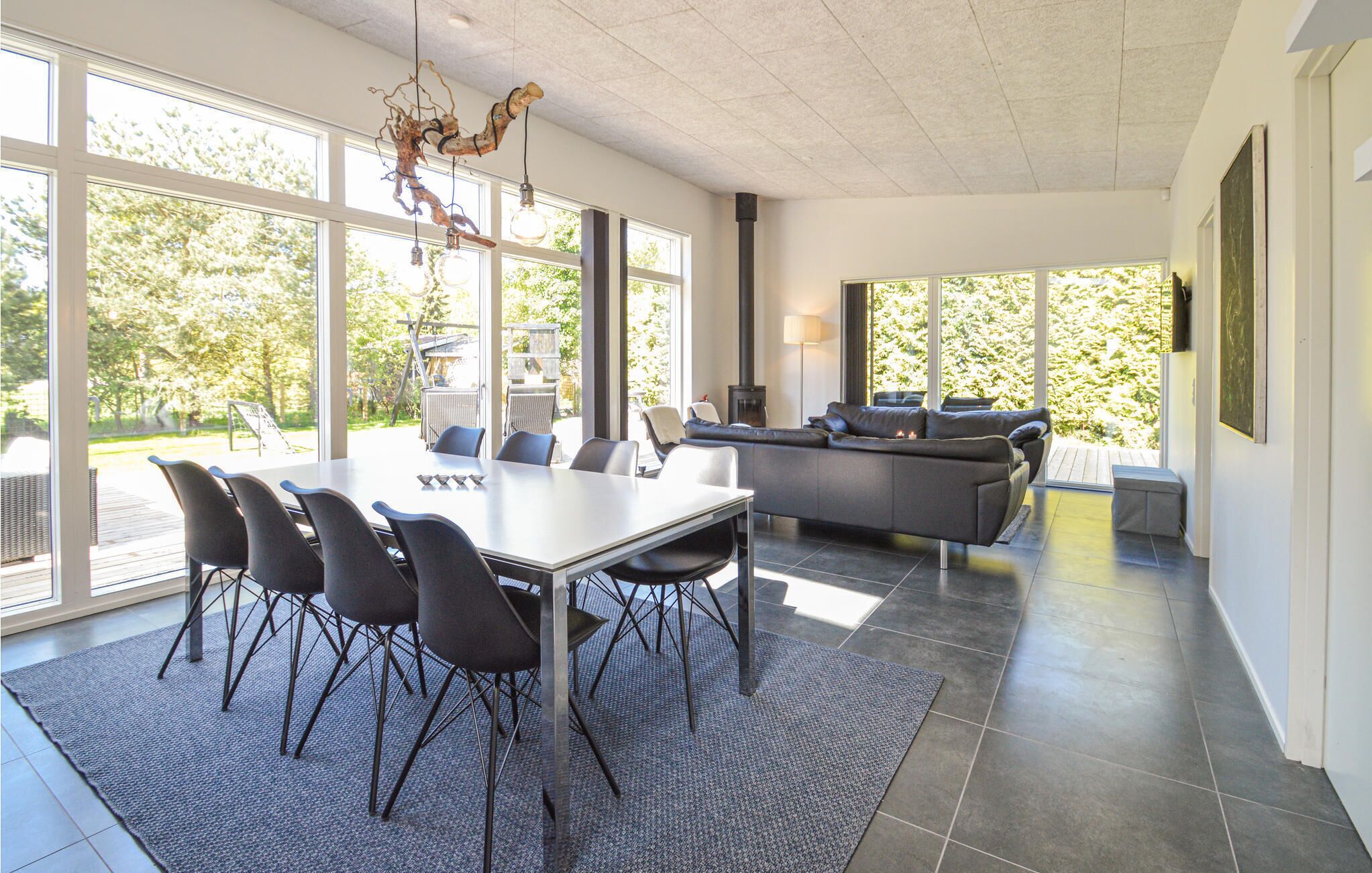 Ein modernes Interieur mit Essbereich, einer Couch und großen Fenstern.