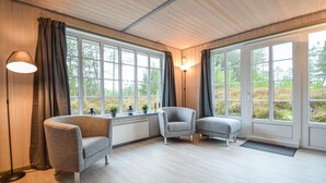 A room with large windows, two grey armchairs, a floor lamp, and a radiator. - Cozy home in Rømø with sauna (Rømø)