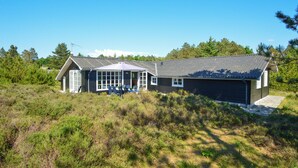 A two-story house with a large porch and a covered outdoor seating area. - Cozy home in Rømø with sauna (Rømø)