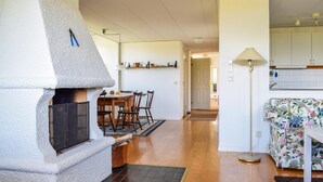 A cozy living room with a fireplace, a dining area, and a kitchen.