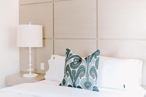A hotel room with a bed, a white lamp, and a patterned pillow. - Mavis - Little Cove (Noosa Heads)