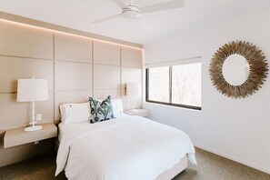 A modern bedroom with a bed, bedside lamps, a ceiling fan, a window, and a decorative wall piece. - Mavis - Little Cove (Noosa Heads)