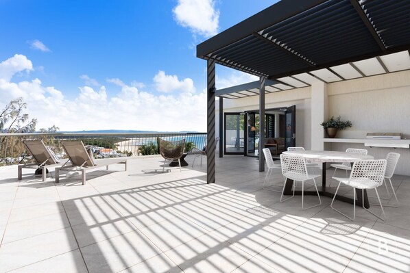 Une terrasse sur le toit, dotée de chaises longues, d’une table à manger et d’une pergola.