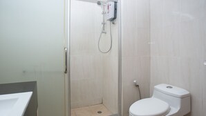 Een badkamer met een douchecabine van glas, een toilet en een wastafel.