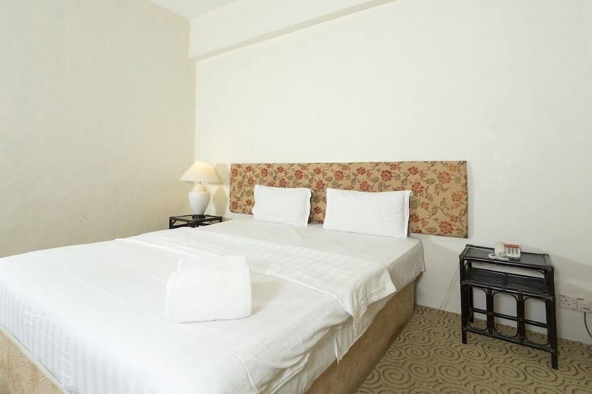 A hotel room with a bed, a nightstand, a lamp, and a telephone.