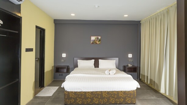 Een hotelkamer met een groot bed, twee nachtkastjes, een schilderij aan de muur en een gordijn voor het raam.