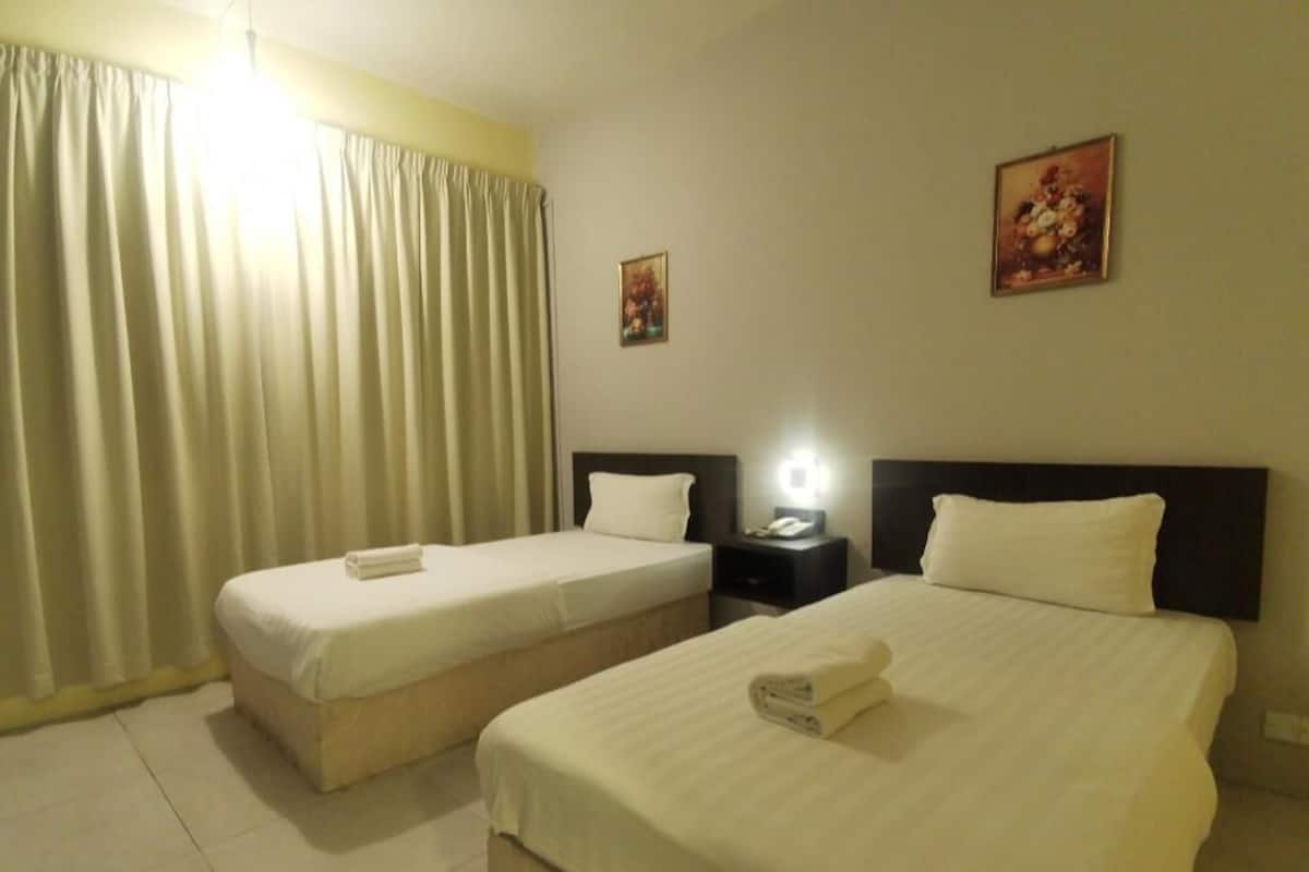 A hotel room with two beds, a nightstand, a lamp, and a painting on the wall.