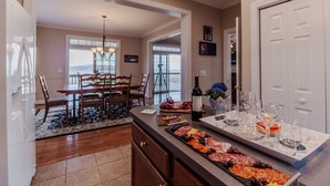 A spacious kitchen with a central island, a dining area with a chandelier, and a view through large windows.