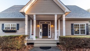 A two-story house with a front porch, a black front door, and a small porch seating area. - Breathtaking Views of Lake Chatuge & Mountain Harbour Golf Course. (Hayesville)