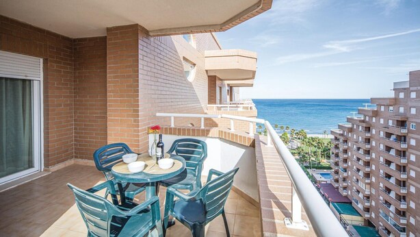 Un balcón con mesa y sillas, con vistas al mar.