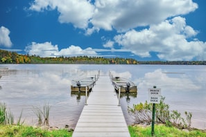 Un molo che conduce a due imbarcazioni identificate come 'Perch Dock' e 'Bass Dock', con un lago calmo e alberi sullo sfondo.