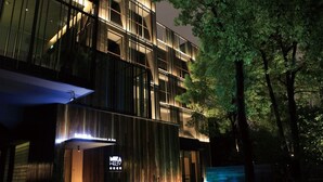 Un bâtiment moderne, agrémenté d’un élément aquatique remarquable à l’avant, illuminé par un éclairage d’ambiance.