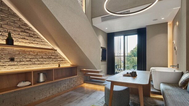 Une cuisine moderne avec un mur en briques, des étagères en bois, un coin repas avec une table et des chaises, et un four encastré.