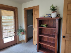 Cozy retreat with a wooden door, window, and bookshelf, featuring a potted plant.