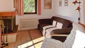 A living room with a fireplace, a sofa, and a lamp. - Les Arsets 01/203 by Interhome (Alpe des Chaux)