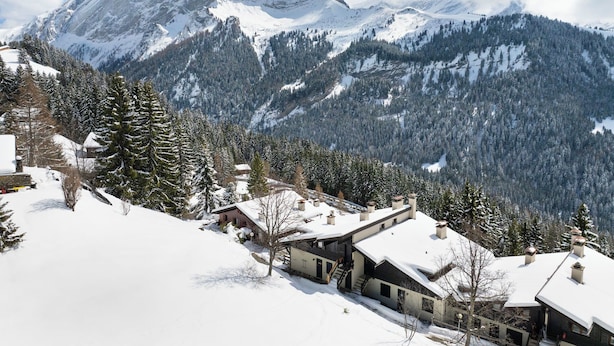 A snow-covered mountain landscape with a modern house featuring a large window and a chimney. - Les Arsets 01/203 by Interhome (Alpe des Chaux)