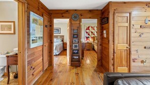 A wooden interior with a hallway leading to a bedroom, a clock, and a bulletin board. - Heavenly Hideaway- Hot Tub, Firepit, Covered Patio, WiFi (Beattyville)