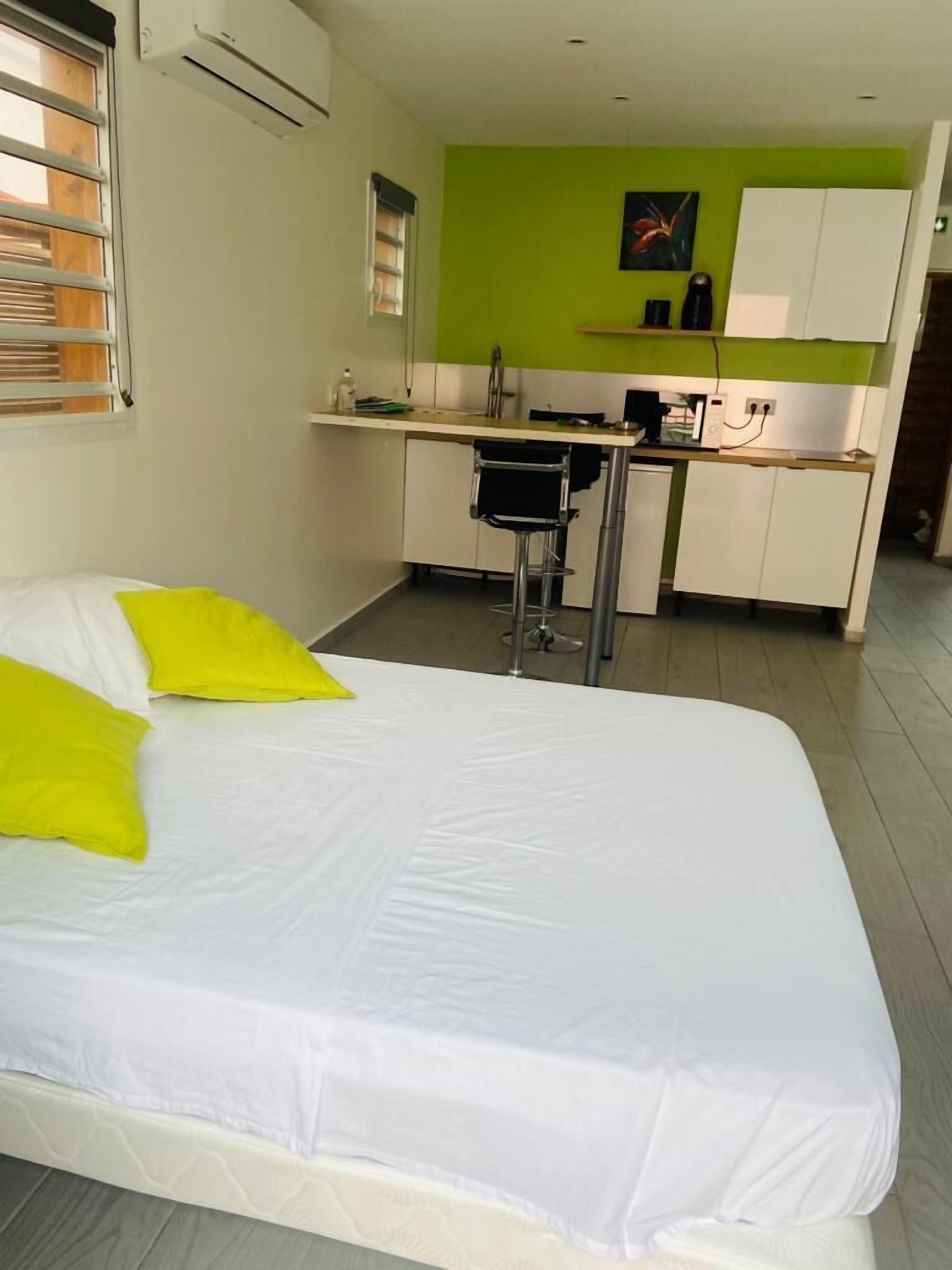 A bedroom with a bed, a small kitchenette, and a bathroom.